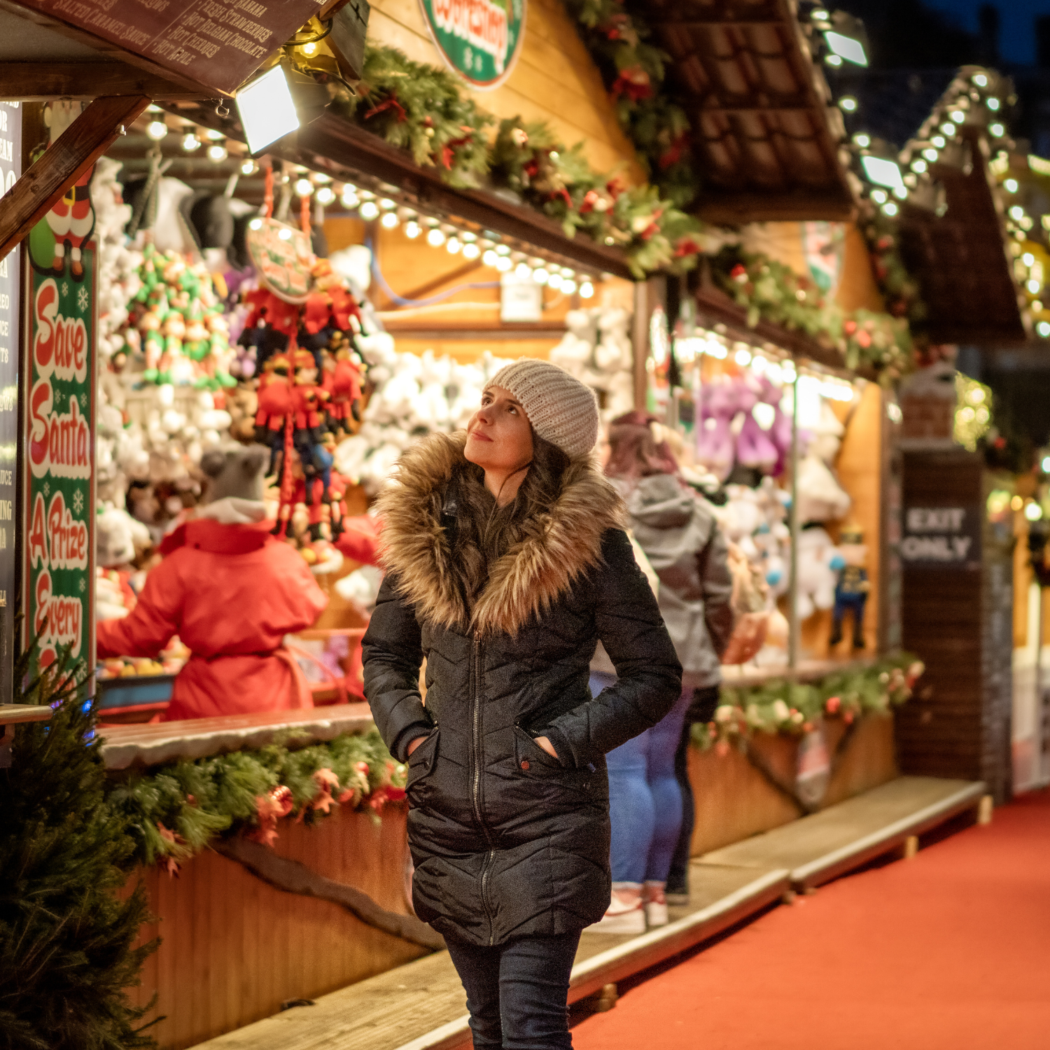 woman walking through christmas market booths in the evening