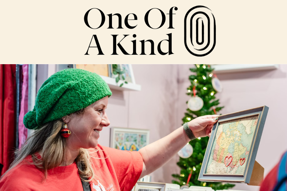 woman looking at a framed map to purchase at the one of a kind show with holiday decorations in the background