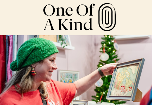 woman looking at a framed map to purchase at the one of a kind show with holiday decorations in the background