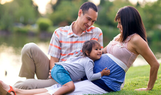 Young family sitting in the grass together