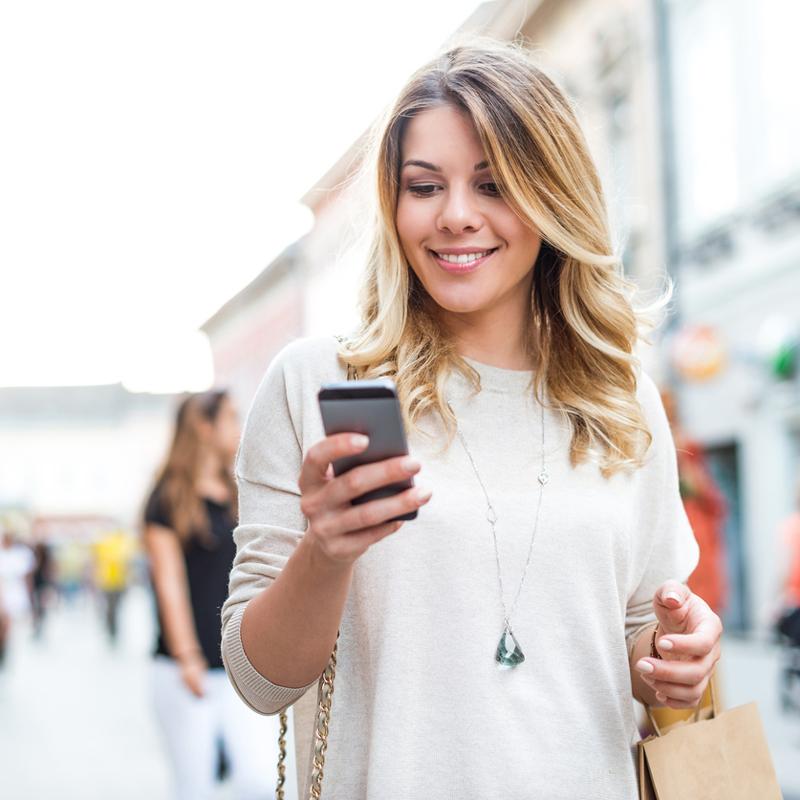 Woman using CAA Rewards app while shopping