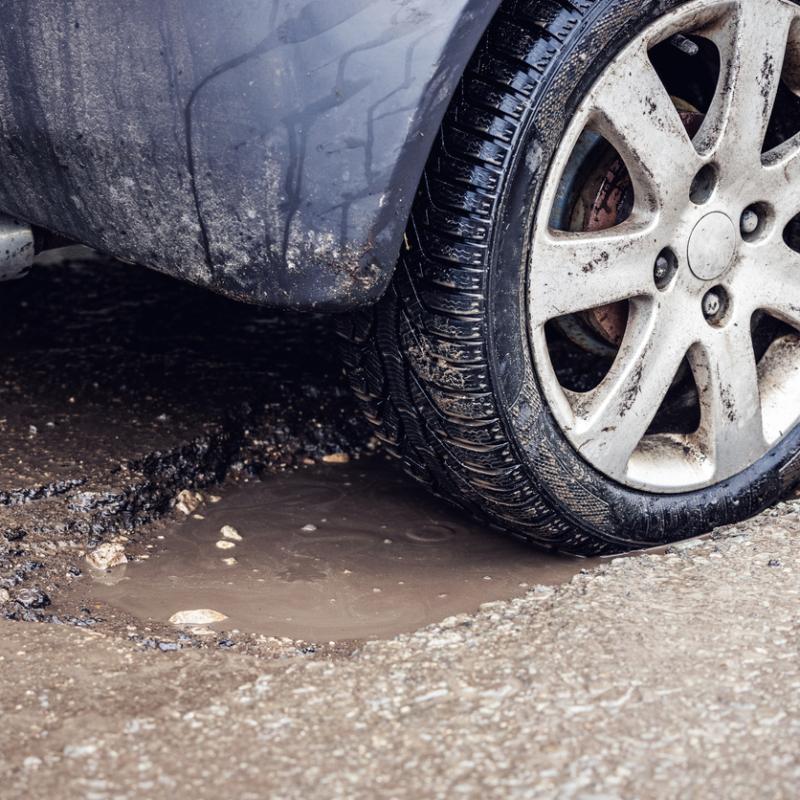 car tire in big pothole on the road