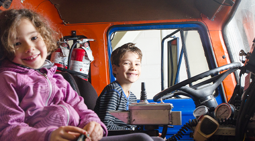 Young girl and boy sitting in a fire truck